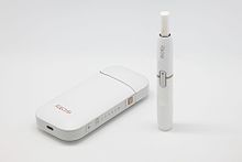 Philip Morris International's iQOS device with charger and tobacco stick.