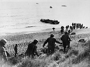 Men running down a cliff towards a waiting boat on the shore