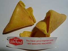 An opened fortune cookie, with the printed fortune that was inside it