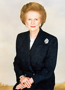 Thatcher in a half-length portrait photograph, wearing a black suit and pearls