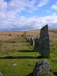 Line of upright, angular stones receding into rolling, grassy terrain