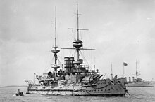 A large gray ship sits at anchor, its guns elevated upward