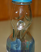 A Codd-neck bottle of Ramune, with the glass marble stopper inside its chamber after the bottle was opened