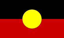 Flagge mit oberer Hälfte in Schwarz, unterer Hälfte in Rot; in der Mitte ist ein gelber Kreis, so hoch wie die Hälfte der Höhe