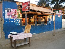 Small wooden table stacked with French bread in front of a storefront kiosk in Toliara