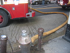 A New York City hydrant hooked to an FDNY fire engine with a fire hose actively pumping water