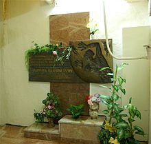 Cross shaped monument with Russian text and flowers