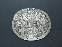 A plaque depicting a bird of prey holding birds in its claws