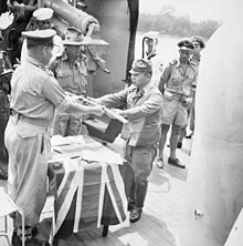 a black and white photograph of a uniformed Japanese officer handing a sword to a uniformed Australian officer