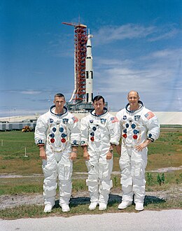 The crew poses with their launch vehicle; left to right, Cernan, Young, Stafford.
