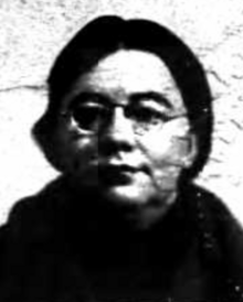 A middle-aged white woman with dark hair, wearing glasses