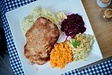 Kotlet schabowy served with potatoes and raw vegetable salads