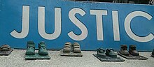 Several bronze sculptures of toddlers's shoes. The phrase "justice" is written in Spanish.