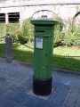 VR pillar box in Kilkenny, Ireland, painted green with obvious door repair