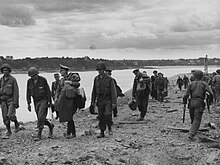Black and white photograph of people in military uniforms near a body of water
