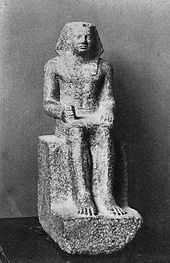 Small statue showing a king seated, wearing the nemes and clenching his right hand