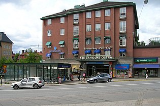 The red building of Stockholm East Station and the entrance to the Stockholm Metro in front of it to the left