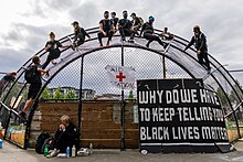 Protesters sitting on a baseball backstop