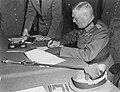 Image 13 German Instrument of Surrender Photograph credit: Lt. Moore; restored by Adam Cuerden The German Instrument of Surrender was the legal document that effected the termination of the Nazi regime and ended World War II in Europe. A July 1944 draft version had also included the surrender of the German government, but this was changed due to concern that there might be no functional German government that could surrender; instead, the document stated that it could be "superseded by any general instrument of surrender imposed by, or on behalf of the United Nations", which was done the next month. This photograph shows Field Marshal Wilhelm Keitel signing the German Instrument of Surrender in Berlin. The first surrender document was signed on 7 May 1945 in Reims by General Alfred Jodl, but this version was not recognized by the Soviet High Command and a revised version was required. Prepared in three languages on 8 May, it was not ready for signing in Berlin until after midnight; consequently, the physical signing was delayed until nearly 1:00 a.m. on 9 May, and backdated to 8 May to be consistent with the Reims agreement and public announcements of the surrender already made by Western leaders.