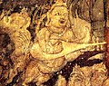 India, in Ajanta Caves, Cave 1, c. 450-490 AD. Kinnara with "kacchapī veena" (Sanskrit for "tortise veena") or panchangi veena (5-stringed veena). Part of the painting Bodhisattva Padmapani.[131][132][note 2]