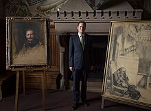 Georg Friedrich Prinz von Preußen posiert stehend und im Anzug zwischen zwei Gemälden.