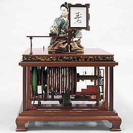 Karakuri puppet, Moji-kaki doll. Using mechanical power, a puppet dips a brush into ink and writes a character on paper.