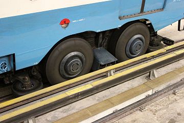 A rubber-tyred metro bogie. Between the two large tires, a contact shoe touches the guidebar and electrically grounds the car.