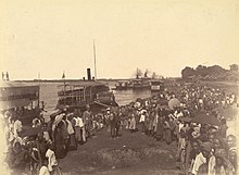 Mounted soldiers disembark surrounded by Burmese onlookers.