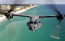 A front view of a U.S. Air Force CV-22 with its rotors facing forward flys by the Emerald Coast