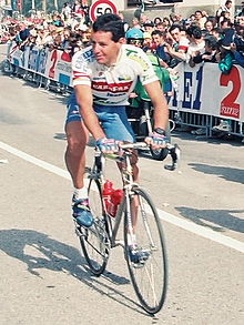 Photograph of Roche from the front, wearing a blue-and-white cycling uniform and riding a racing bicycle