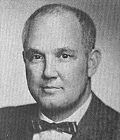 Portrait of middle-aged man. He wears a bowtie with his suit.