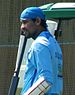 A Sri Lankan cricketer wearing a blue shirt and a blue cloth of his head. He also has a guard on his hand.