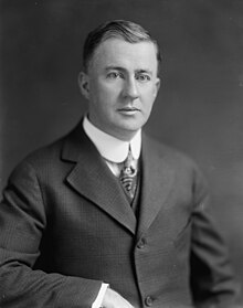 Black-and-white photograph of a clean-shaven man with his hair cut short, at about 45. He is wearing a suit and tie in a style common in the 1910s and 1920s.