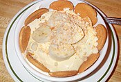 Banana pudding is prepared with vanilla flavored custard, cookies and sliced fresh bananas, topped with whipped cream or meringue.
