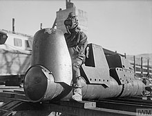 Black and white photograph of a small sea craft with a man wearing a rubber suit seated on it