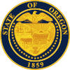 A navy blue seal with gold lettering and imagery. The seal contains a shield, supported by 33 stars and with an eagle with its wings spread on top; "STATE OF OREGON" is written above the eagle and "1859" appears below the shield. Within the shield appear a sun with its rays extending to two ships and a mountain and trees, two oxen pulling a covered wagon, and a ribbon containing "THE UNION".