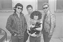 The band standing, with Exene holding a cat