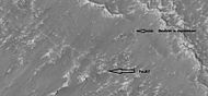 Close-up of a cliff showing possible faults, as seen by HiRISE under HiWish program; note the rock that seems to be split by the fault. Some boulders are sitting in round holes because their ability to gather and hold heat may have melted ground ice.