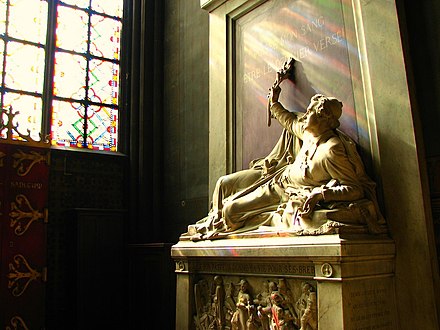 The tomb of Archbishop Affre (1793–1848) in the Chapel of Saint-Denis. The sculpture depicts the archbishop's mortal wounding during the June Days uprising while holding an olive branch as a sign of peace. The inscription reads Puisse mon sang être le dernier versé! ("May my blood be the last shed!").