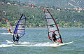 Windsurfers on the river with a forested hillside in the background