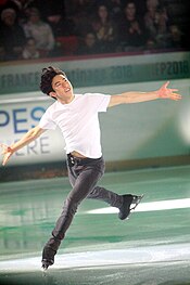 A photograph of Nathan Chen skating during an exhibition under colourful lights.