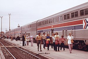 Row of silver double-deck coaches with red-white-blue striping in the middle