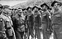 Soldiers wearing slouch hats lined up on parade as a reviewing officer conducts an inspection