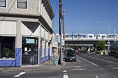 Photograph of buildings on the left with a Green Line train crossing a bridge in the background