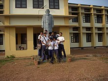 Students in official school uniform in front of the statue of Tagore at the entrance of the school.