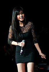 A woman wearing a black mini dress and holding hand-held microphone