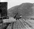 Collapsed Ludendorff Bridge with sign posted by the US Army: "CROSS THE RHINE WITH DRY FEET COURTESY OF 9TH ARM'D DIV"