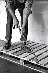 A man using a crowbar to dismantle a wooden pallet