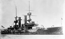 A large, dark warship sits at anchor