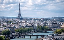 Farbfotografie in der Obersicht von Paris mit dem Fluss und drei Brücken im Vordergrund. Der Fluss verläuft von links unten nach rechts bis zum Musée d’Orsay. Hinten links ist der Eiffelturm und hinten rechts der Palais de Chaillot.